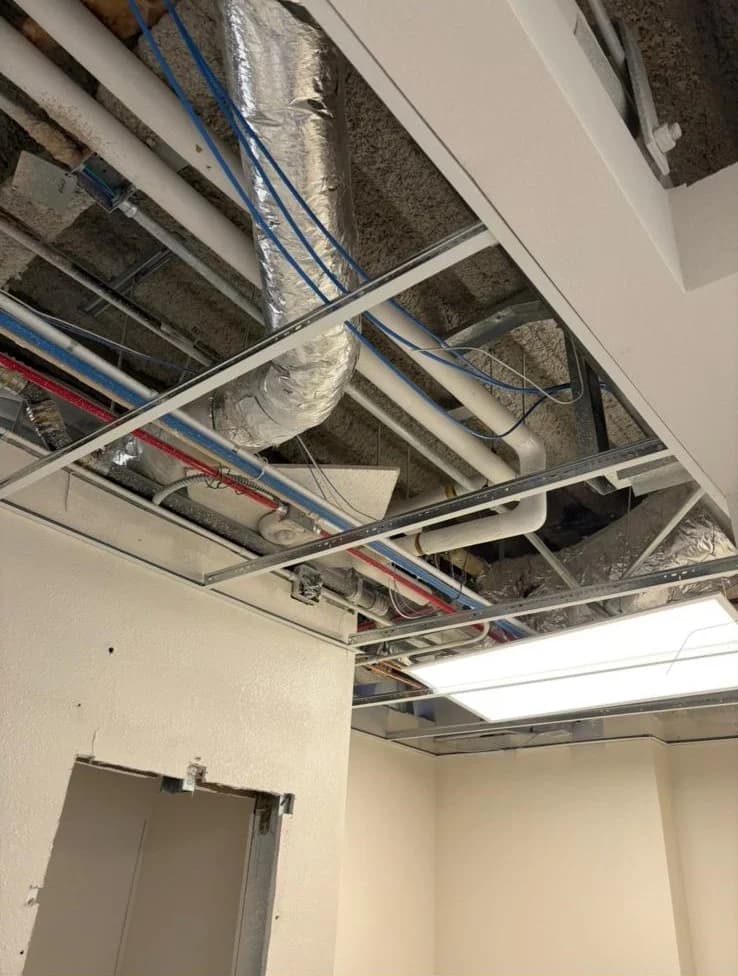 Close-up of ceiling grid track and mechanical rough-in above a drop ceiling