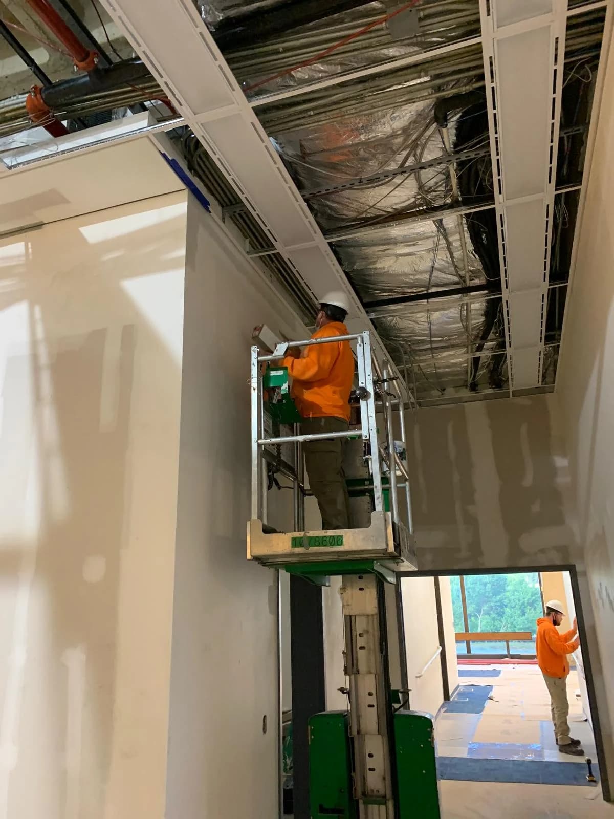 SCG crew member on a lift working on a commercial ceiling grid