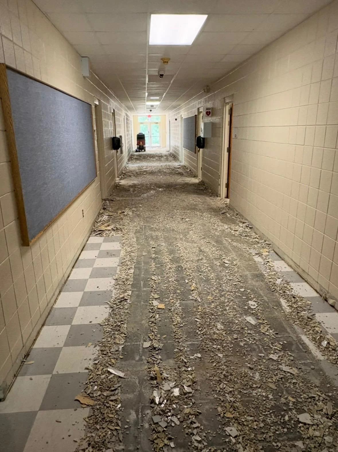Commercial hallway mid-demolition, flooring torn out and debris cleared to the sides