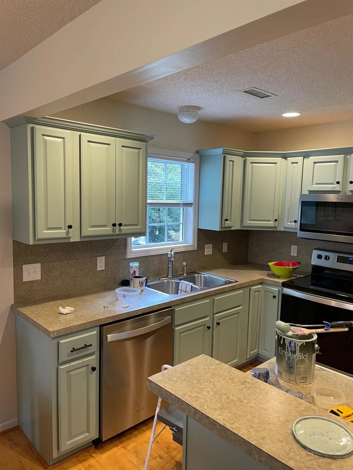 SCG crew repainting kitchen cabinets sage green during a real residential job
